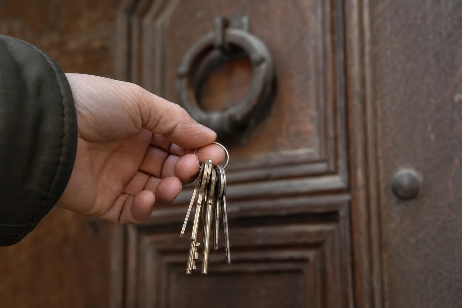 Trousseau de clés tendu devant une porte d’entrée en bois, le jour de la remise
